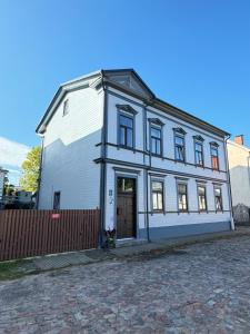 a large white building with a door and a fence at 555 метров до моря in Liepāja