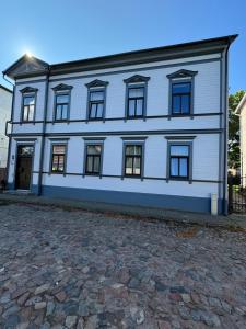 a white building with windows on a cobblestone street at 550 метров до моря in Liepāja
