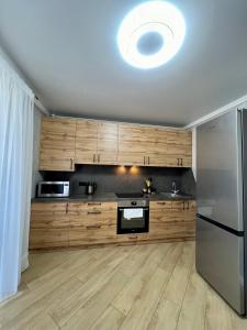a kitchen with wooden cabinets and a stainless steel refrigerator at Затишна квартира біля парку Центр міста in Ternopilʼ