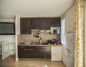 eine Küche mit dunkelbraunen Schränken und einem TV in der Unterkunft Voltaire Elephant Suite - 5 min Hypercentre in Troyes + 3 Fotos
