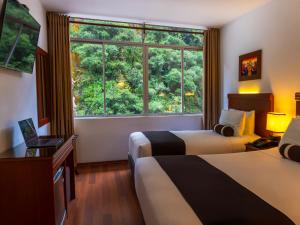 una camera d'albergo con due letti e una grande finestra di Hotel Ferré Machu Picchu a Machu Picchu