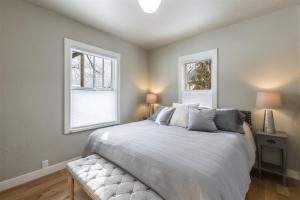 a bedroom with a large white bed with two windows at Bluebird Day - Fuller Cottage in Bend