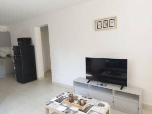 a living room with a flat screen tv and a table at T2 terrasse couverte proche Pont du Gard et Uzès in Pouzilhac