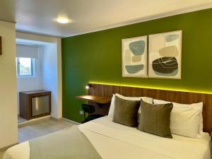 Un dormitorio con una cama y una pared verde. en 122 Plaza Apartahotel, en Bogotá