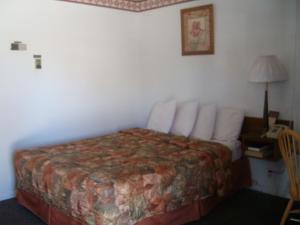 a hotel room with a bed and a desk with a lamp at Western Motel Ranchester in Ranchester