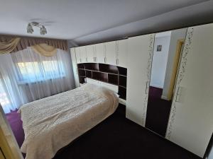 a small bedroom with a bed and white cabinets at Vila Medana- Neamt in Humuleşti