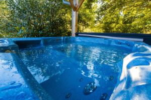 a blue hot tub with trees in the background at Home - Retour aux sources in Le Ménil