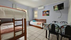 a bedroom with two bunk beds and a table and a television at GH Canal da Barra in Florianópolis