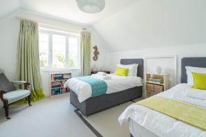 Un dormitorio con dos camas y una silla y una ventana. en Chantries, en Bembridge