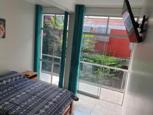 a bedroom with two windows and a bed and a television at los pintores in Tingo María