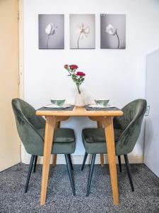 a dining room table with green chairs and a vase with flowers at Blissful apartment in Sheffield +12 photos