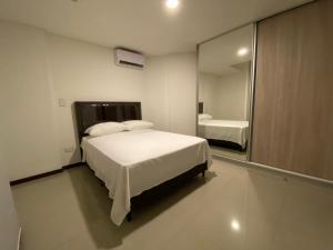 a bedroom with a white bed and a large mirror at Dpto 1 Dorm y balcon Baruc 3 Como en Casa - Scz in Santa Cruz de la Sierra +13 photos