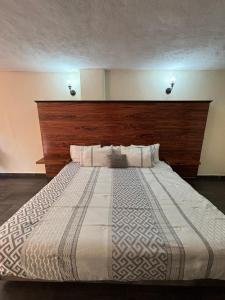 a bedroom with a large bed with a wooden headboard at Hotel Narváez Dorado Centro de Convenciones in Tuxtla Gutiérrez