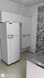 a white kitchen with white cabinets and a refrigerator at Casa Duplex com Vista pro Mar in Guaratuba