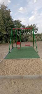 une aire de jeux avec une balançoire verte et rouge dans l'établissement Cortijo El Pajaroto, à Matanegra