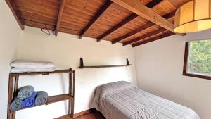 a bedroom with a bed and a shelf with towels at Casa Moderna entre Coihues in San Carlos de Bariloche