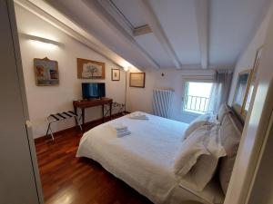a bedroom with a white bed and a television at B&B Griffoni 7 in Bologna