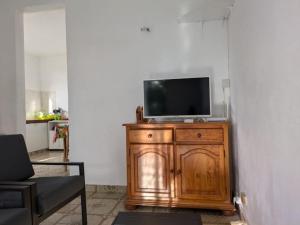 a television on a wooden cabinet in a living room at Maison F4 à Sainte - Anne, Guadeloupe in Sainte-Anne