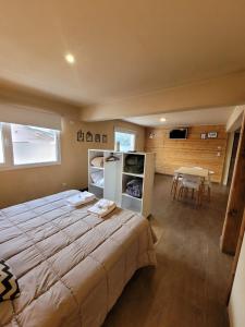 a large bed in a room with a table at Baguales Alojamientos Patagonicos in Villa La Angostura