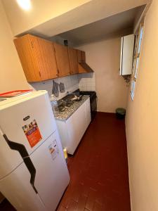 a small kitchen with a white refrigerator and cabinets at Cómodo departamento centrico a metros de la Catedral in San Fernando del Valle de Catamarca