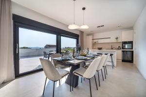 a dining room with a table and chairs and a large window at Villa Mia with Heated Pool in Maslenica