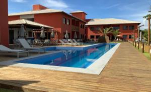 a swimming pool next to a resort with chairs and umbrellas at Vista espetacular em Itacimirim in Itacimirim