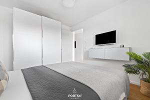 a white bedroom with a bed and a flat screen tv at Ferienwohnung Harbour Side, App 7 Olpenitz in Olpenitz