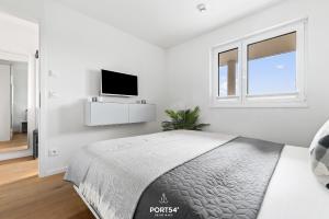 a white bedroom with a bed and a flat screen tv at Ferienwohnung Harbour Side, App 7 Olpenitz in Olpenitz +19 photos