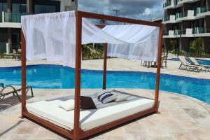 łóżko z baldachimem przed basenem w obiekcie Flat Makia Beach Experience 120C - Muro Alto - Porto de Galinhas w mieście Cupe