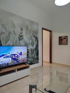 Una sala de estar con televisión y un mural. en Casa Maria, en Iglesias