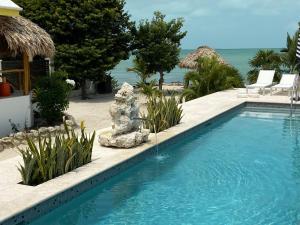a swimming pool next to a resort with the ocean at Casa Cava Bed & Breakfast in San Pedro