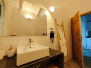 une salle de bain avec un lavabo blanc et un miroir dans l'établissement Casa dos Castanheiros - The White Cottage, à Canto da Areia