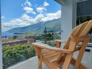 une chaise en bois assise sur un balcon avec vue dans l'établissement Casa dos Castanheiros - The White Cottage, à Canto da Areia