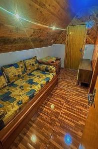 a bedroom with a couch and a wooden floor at Chalé Sossego 3 in Campos do Jordão