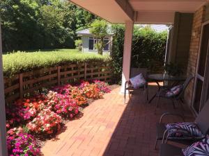a patio with flowers and a table at Bethlehem Garden Retreat in Tauranga