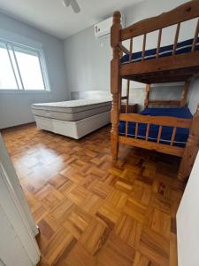 a bedroom with two bunk beds and a wooden floor at Vista Maravilhosa Pitangueiras in Guarujá