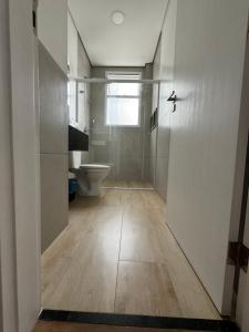 a bathroom with a toilet and a hallway with a door at Vista Maravilhosa Pitangueiras in Guarujá +12 photos