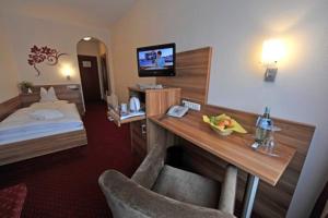 ein Hotelzimmer mit einem Bett und einem Schreibtisch mit einem TV in der Unterkunft Hotel Nothnagel in Darmstadt