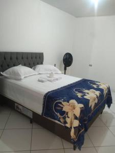 a bed with a blue and white blanket on it at Apê 05 confortável perto de tudo in Vitória da Conquista