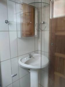 a white bathroom with a sink and a mirror at Apê 05 confortável perto de tudo in Vitória da Conquista