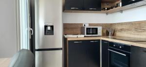 a kitchen with black cabinets and a microwave at Le Senghor in Courcouronnes