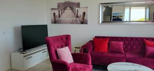 a living room with a red couch and a tv at Le Senghor in Courcouronnes