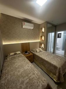 a bedroom with two beds and a air conditioner at Apartamento 203 Maré cheia Praia de Bombas in Bombinhas