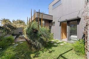 a house with a yard with palm trees at Banksia Coastal Retreat in Point Lonsdale