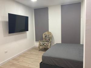 a bedroom with a bed and a chair and a flat screen tv at 2325 Apartaestudios in Arauca