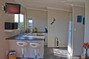 a kitchen with a counter and two stools in it at Orca Lodge in Raglan