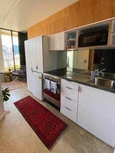 a kitchen with white appliances and a red rug at Cosy Penthouse Apartment in Wellington +1 photo