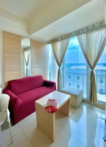 a living room with a red couch and a large window at Onebad room - 1 ruang Tv & 1 Kamar tidur at Treepark serpong in Dadap