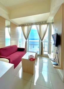 a living room with a red couch and a large window at Onebad room - 1 ruang Tv & 1 Kamar tidur at Treepark serpong in Dadap