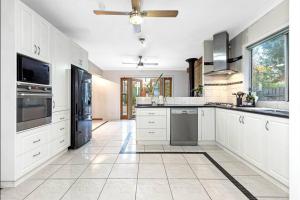 a large kitchen with white cabinets and appliances at Updated Cottage on Large Sunny Block - 5 mins-CBD in Canadian
